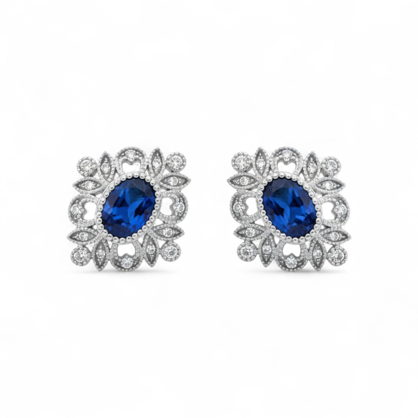 Pair of earrings with blue gemstones and silver floral designs on a white background