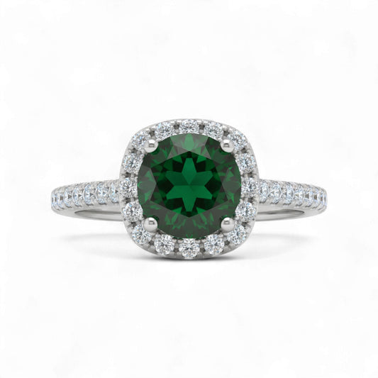 Ring with a green gemstone and diamond halo on a white background