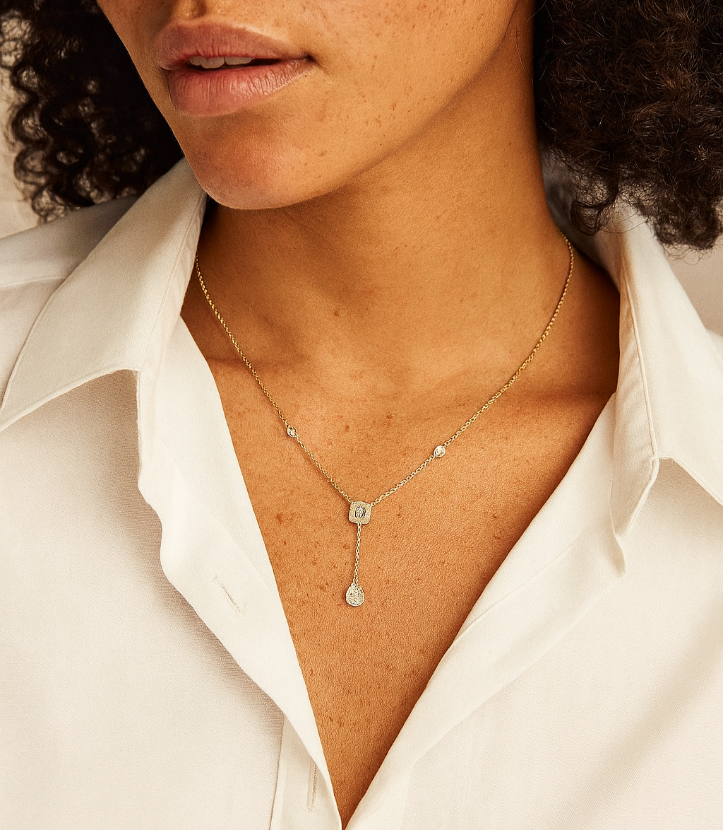 Close-up of a person wearing a delicate necklace with a white shirt.