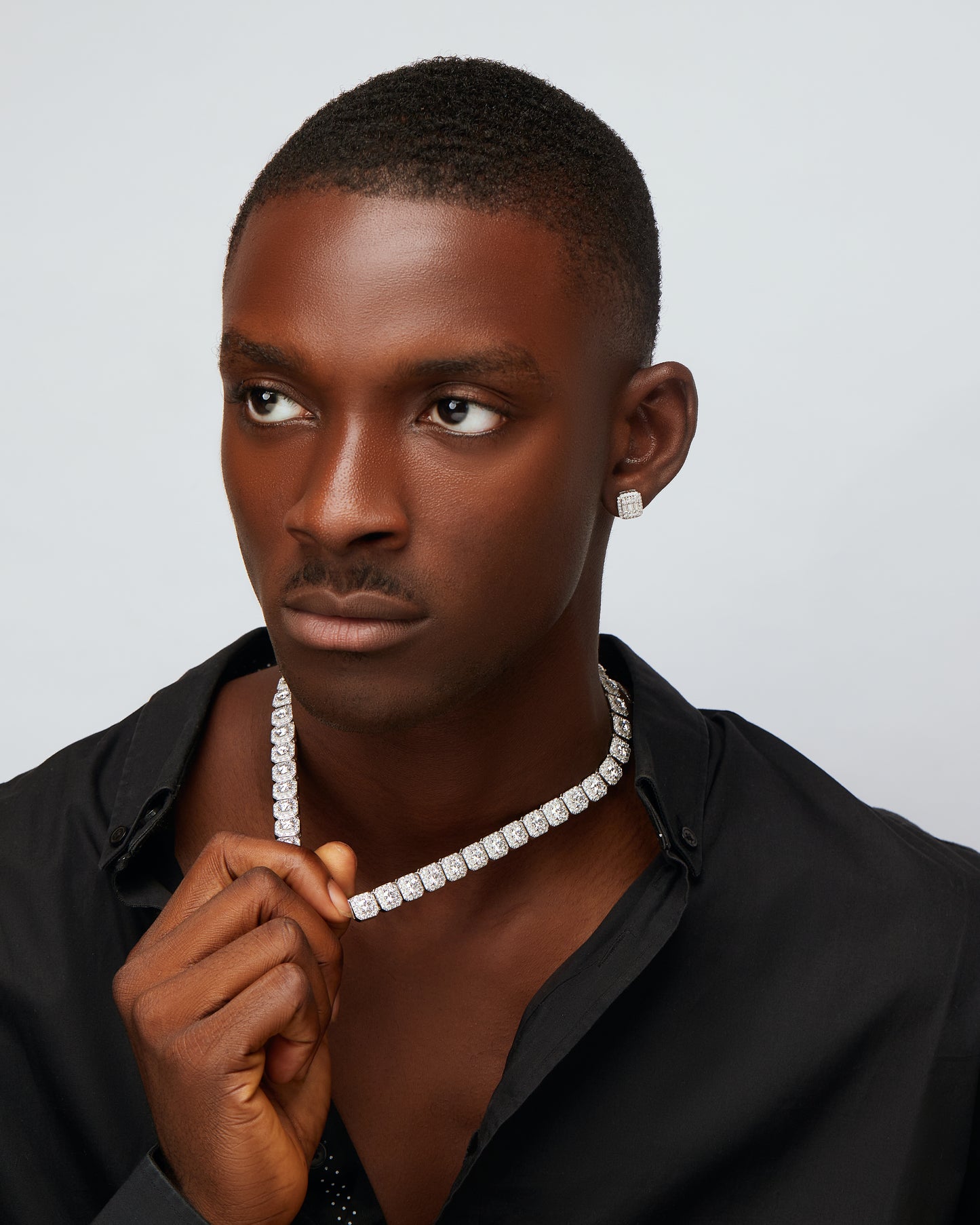 Man wearing a diamond necklace against a plain background