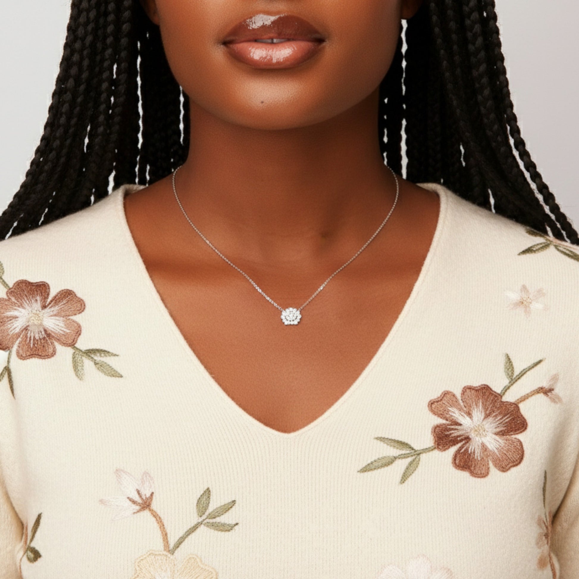 Woman wearing a silver necklace with a floral pendant against a neutral background