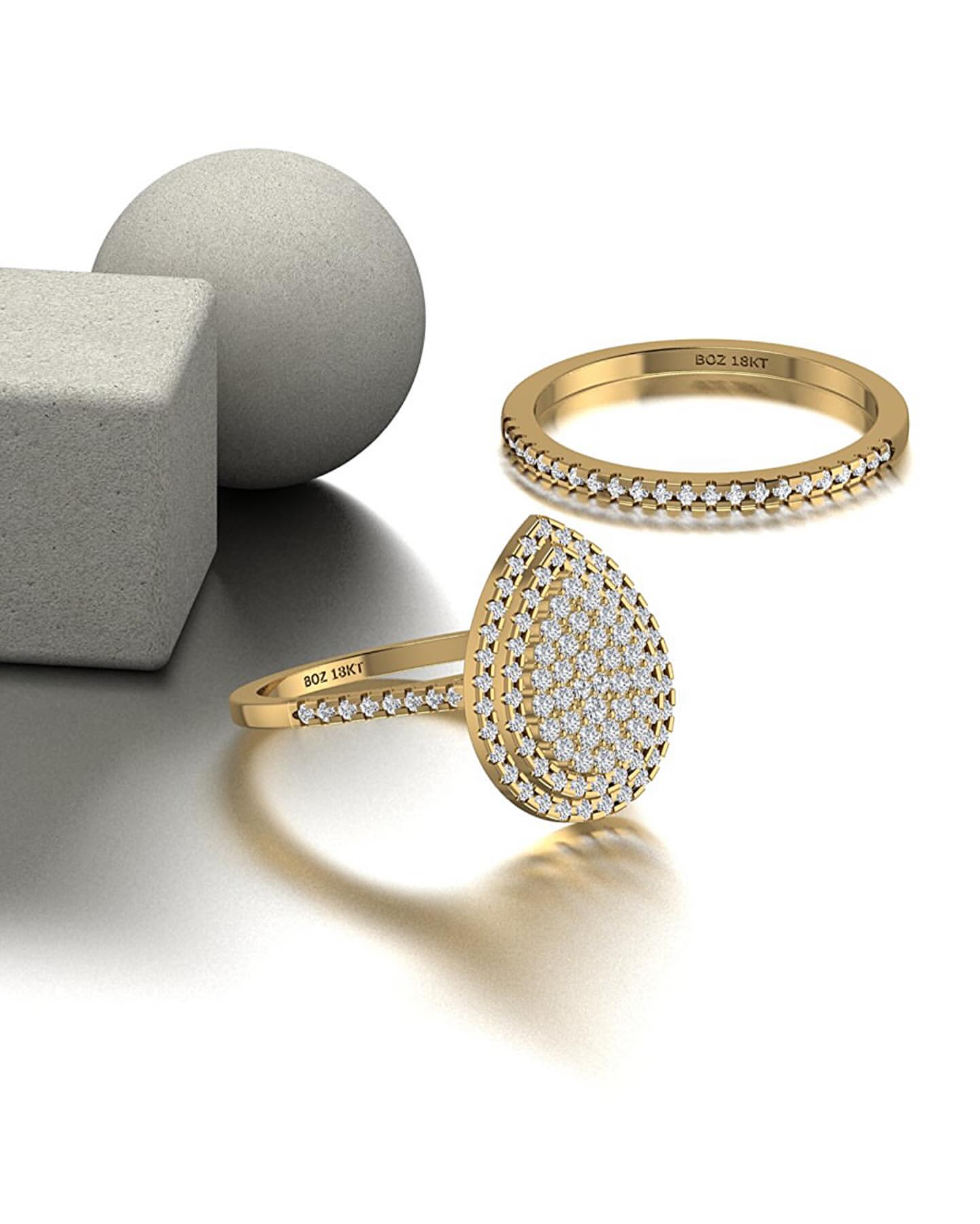 A set of three 18K gold rings, with the central ring featuring a pear-cut natural diamond cluster, surrounded by two smaller rings.