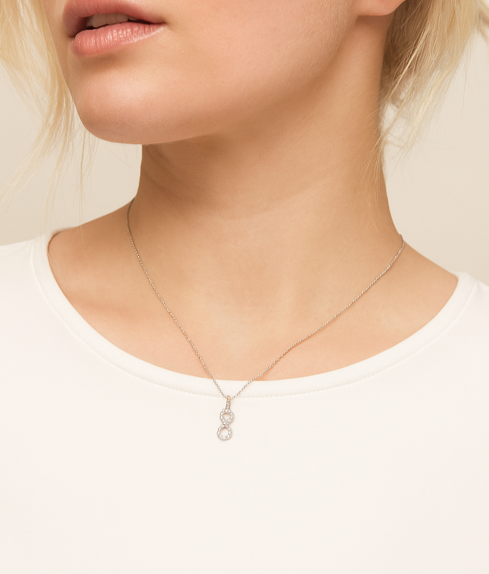 Close-up of a person wearing a delicate necklace with a small pendant on a plain background