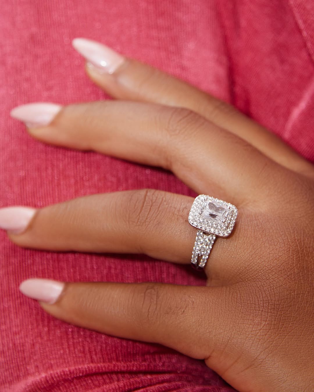 A person's hand displaying a radiant cut engagement ring with a 10 karat gold band.