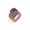 Rose gold ring with black gemstones on a white background