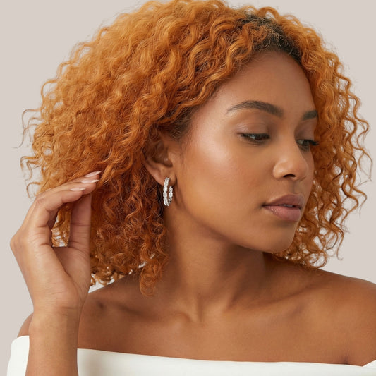 Woman with styled hair and earrings against a neutral background