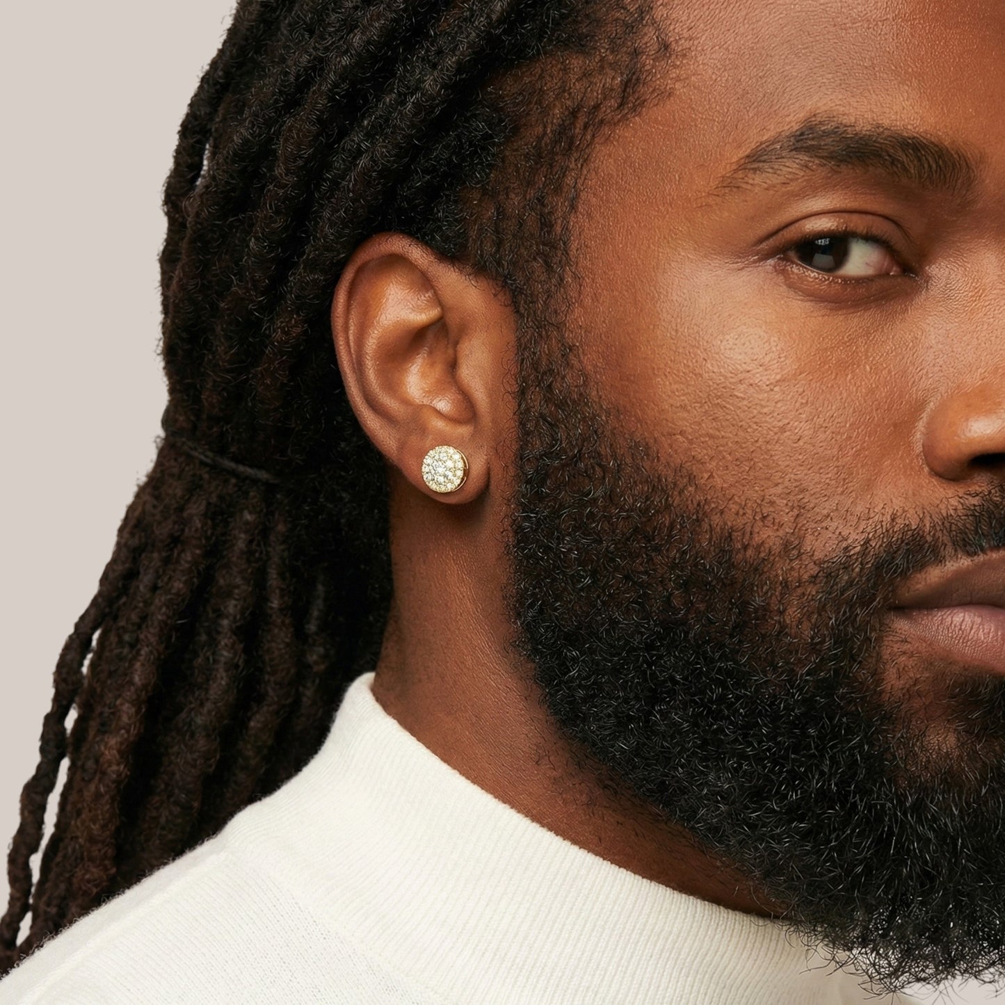 Close-up of a person wearing a diamond earring with a neutral background