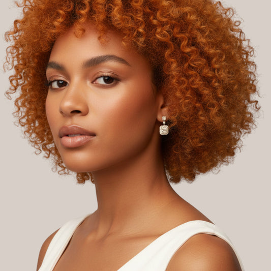 Woman with curly orange hair wearing a white top against a neutral background