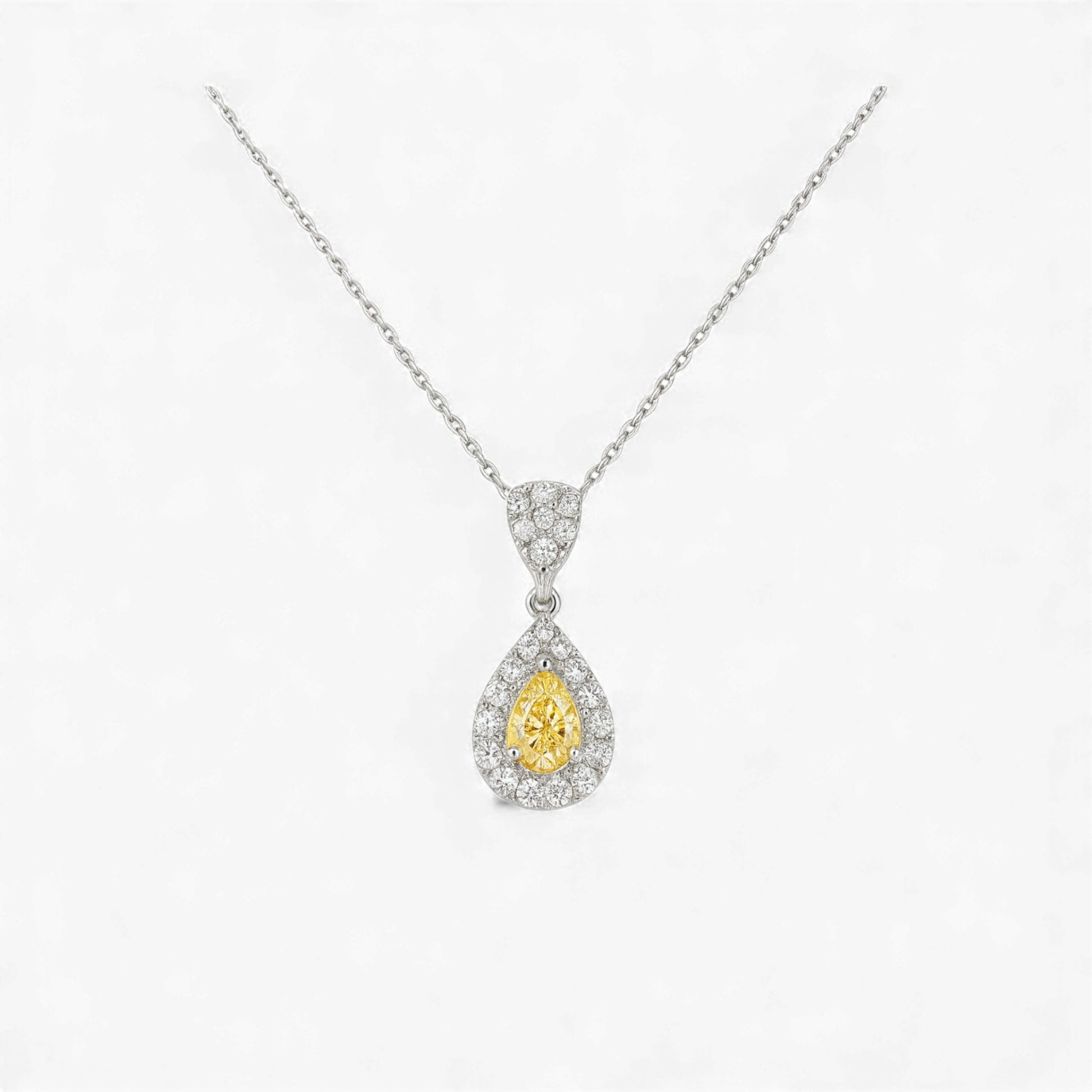 Teardrop-shaped yellow gemstone pendant with diamond accents on a white background