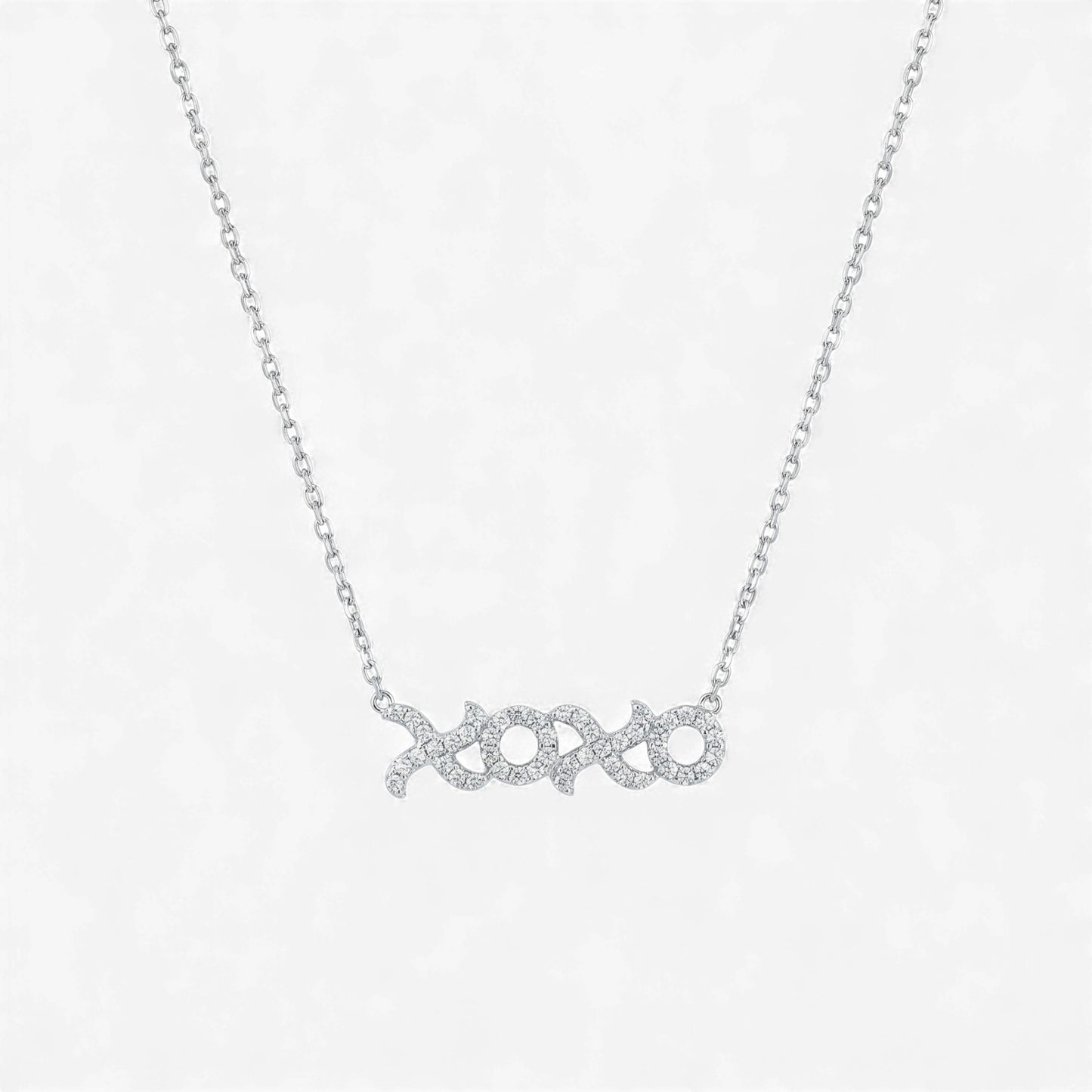 Silver necklace with 'xoxo' pendant on a light gray background