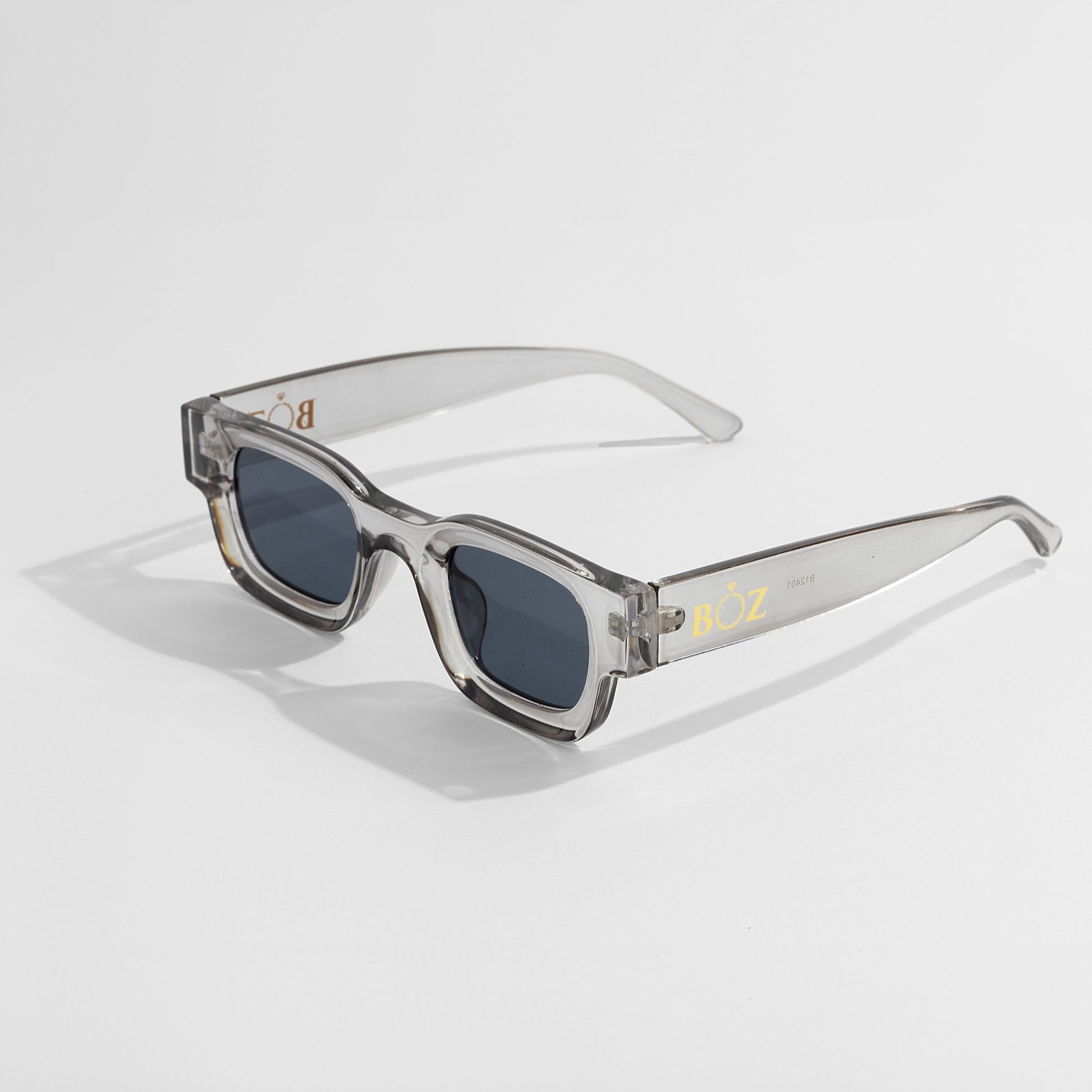 Sunglasses with clear frame and dark lenses on a light gray background
